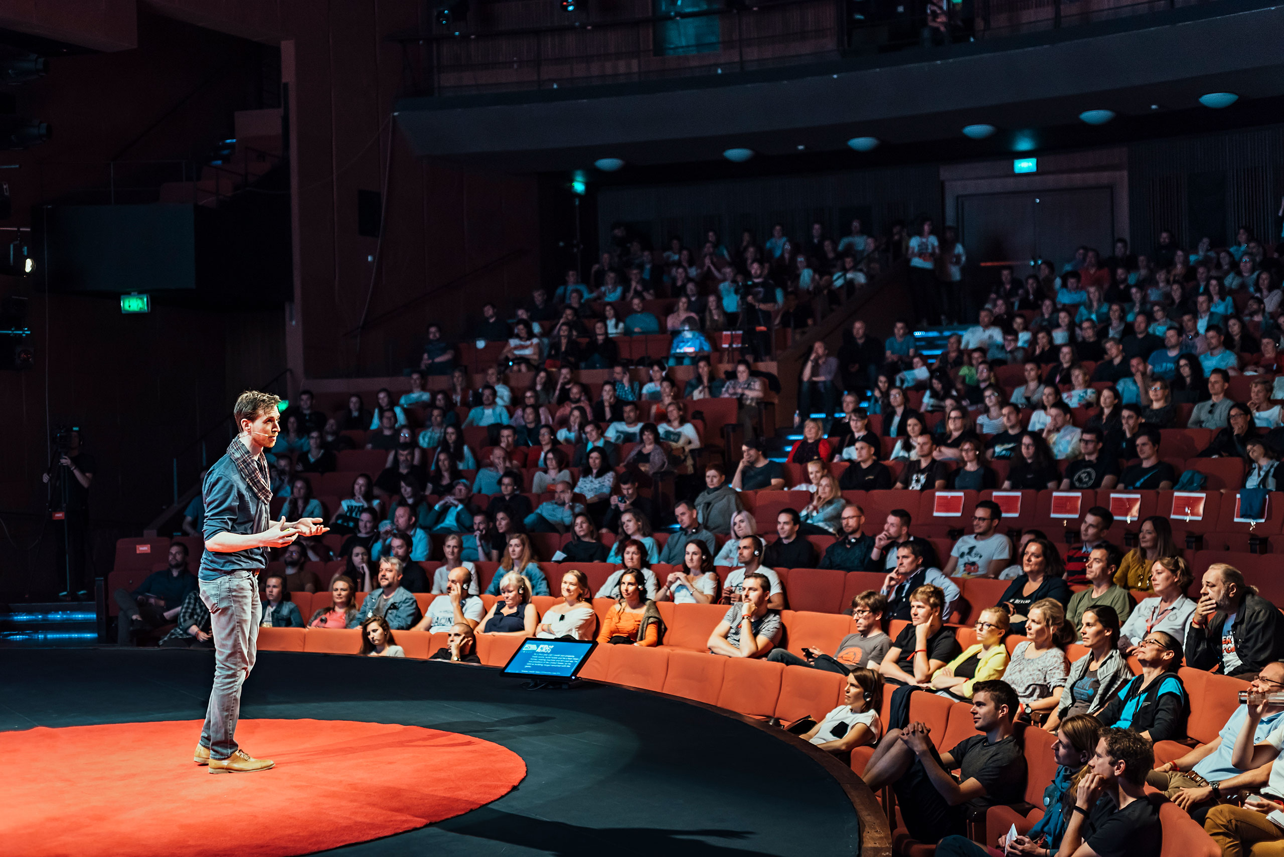 Jonathan Bobrow standing on a red carpet presenting to an audience in stadium seating